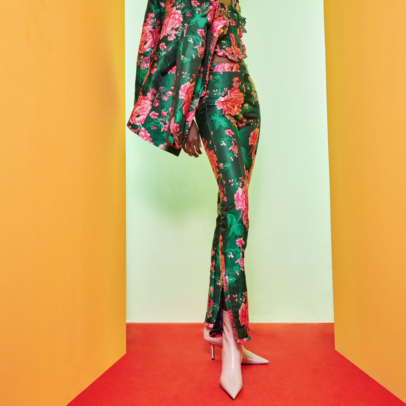 Model posed in green, rose-printed Falu Pants, Trebol Top, and Tango Jacket all from Celia B. 